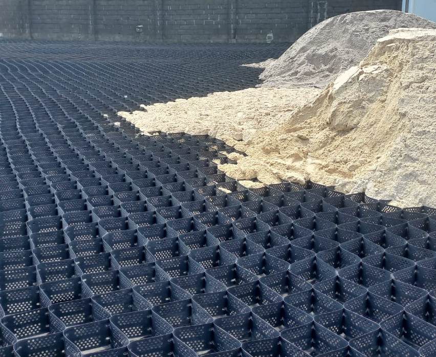 Black geotextile grid on orange dirt — port scour protection